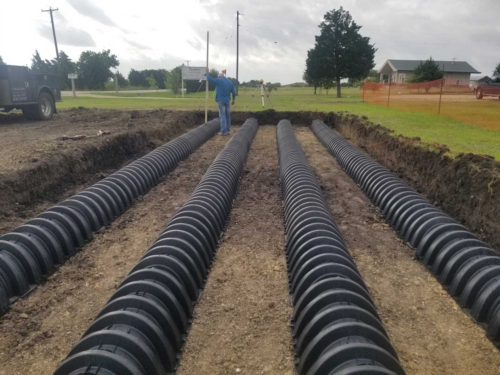 “Commercial septic tanks being installed in a prepared trench with heavy equipment in Central Texas.”