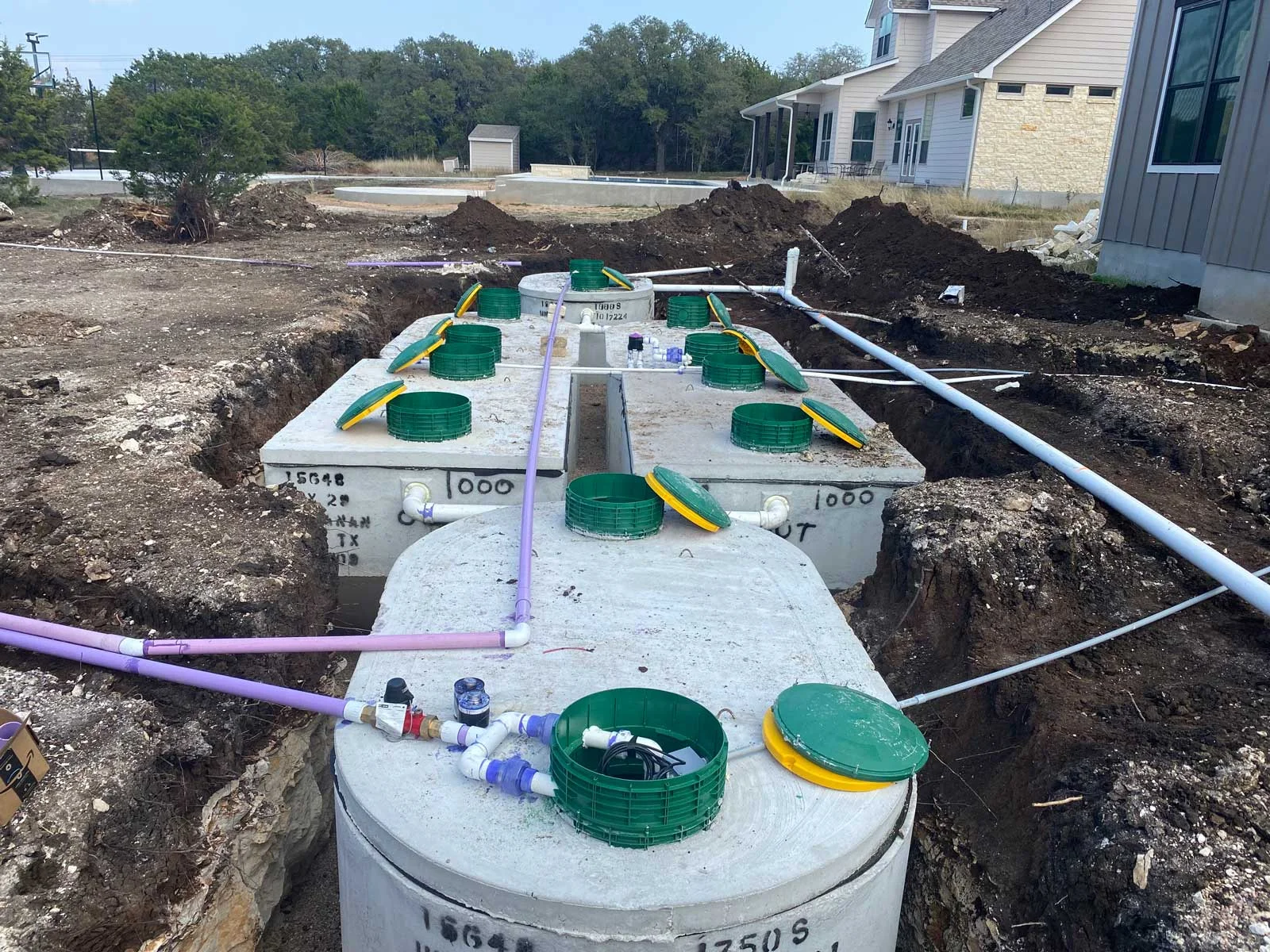 “Residential septic system installation beside a Texas home with concrete tanks and PVC piping.”